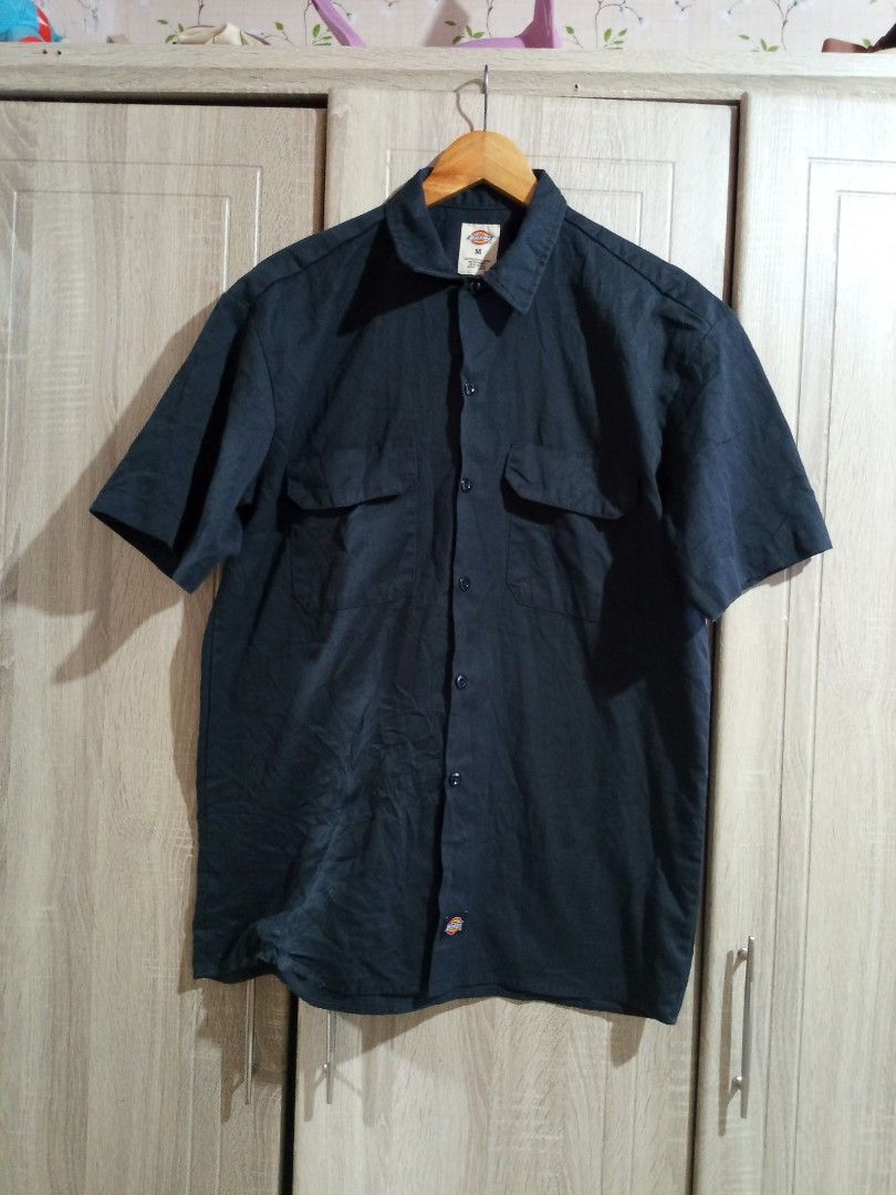 Dickies Black Short Sleeve Work Shirt (Category: Tshirts & Polo Shirts ) located in Manila. Submitted by genitereym17524 (Listing ID 1469547236, Image 1). Description: - w22 L29.5 issue maliit lang Color rate 9.5 Brand: Dickies - Item: Button-down short sleeve shirt - Color: Solid black - Size: Medium (tag at collar) - Pockets: Dual chest pockets with flaps - Details: Front button closure, woven logo patch near hem and sleeve cuff - Material: Stu