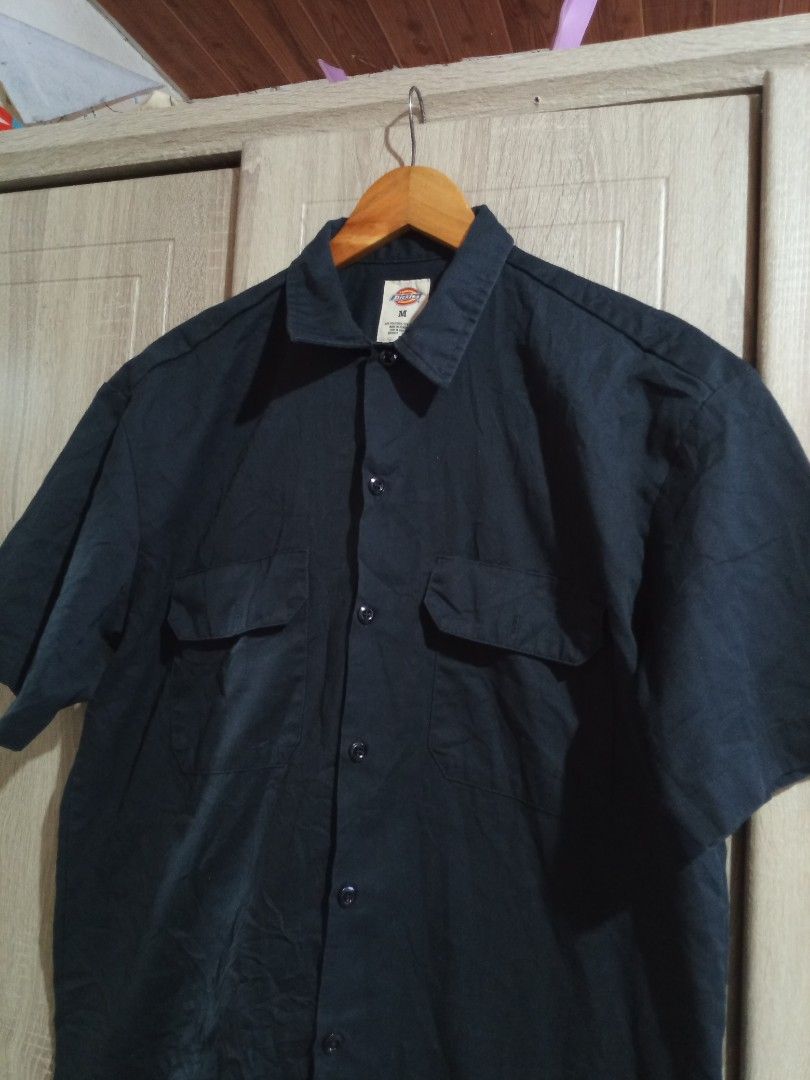 Dickies Black Short Sleeve Work Shirt (Category: Tshirts & Polo Shirts ) located in Manila. Submitted by genitereym17524 (Listing ID 1469547236, Image 3). Description: - w22 L29.5 issue maliit lang Color rate 9.5 Brand: Dickies - Item: Button-down short sleeve shirt - Color: Solid black - Size: Medium (tag at collar) - Pockets: Dual chest pockets with flaps - Details: Front button closure, woven logo patch near hem and sleeve cuff - Material: Stu