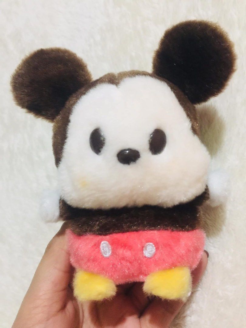 Disney Mickey Mouse (Category: Plushies & Soft Toys) located in Baguio. Submitted by izza_thrifty (Listing ID 1469505237, Image 1). Description: Disney Mickey Mouse plush toy. Brown and white fur, red shorts with white buttons, yellow feet. Attached Disney tag reads FAC-024566-23297, Made in China. Soft material, bean-filled body style. Small brown tail at the back. Minor yellow stain near the left cheek area..