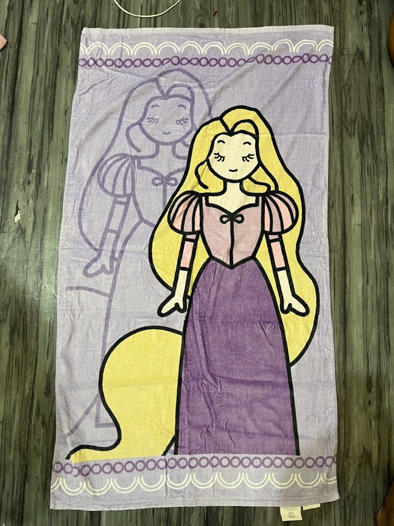 Disney Princesa Rapunzel Beach Towel (Category: Bedding & Towels) located in Manila. Submitted by kaye012222 (Listing ID 1469398393, Image 1). Description: - Official Disney Princess Rapunzel design in lovely purple and yellow - Material: 100% soft, high-quality cotton - Features vibrant printed graphics on the front with a plain white terry loop backing - Brand new with official Disney merchandise tag attached - Perfect for beach trips, pool day
