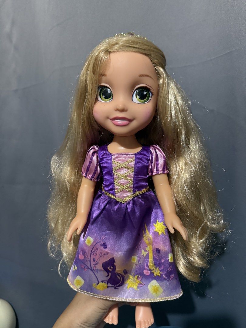 Disney Princess Rapunzel Toddler Doll (Category: Kids Toys) located in Las Pinas. Submitted by yourboki.2026 (Listing ID 1469411463, Image 2). Description: - Authentic Disney Rapunzel toddler doll - Features long, neatly brushed blonde hair and striking green eyes - Wears her signature purple dress with cute lantern graphics and gold trim - Comes with a matching small tiara - Clean outfit with vibrant, bright colors.