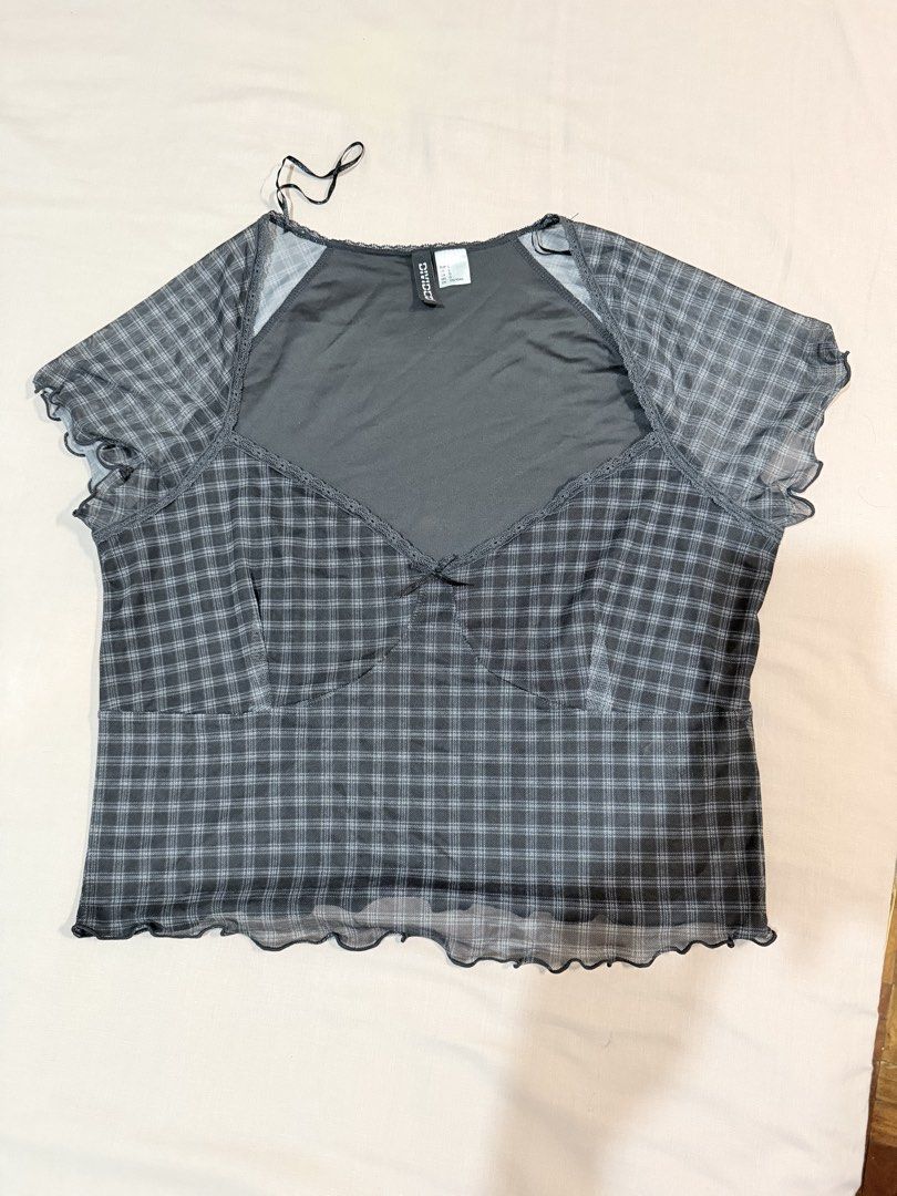 Divided H&M Black Plaid Mesh Lettuce Hem Top (Category: Sleeveless) located in Paranaque City. Submitted by hannahking36 (Listing ID 1469552263, Image 2). Description: - Brand: Divided - Size: L - Color: Black and grey plaid - Style: Y2K aesthetic, double-layered sheer mesh with solid underlayer - Details: Short sleeves with lettuce edges, sweetheart neckline, and front bow detail - Fit: Stretchy, comfortable, and flattering.