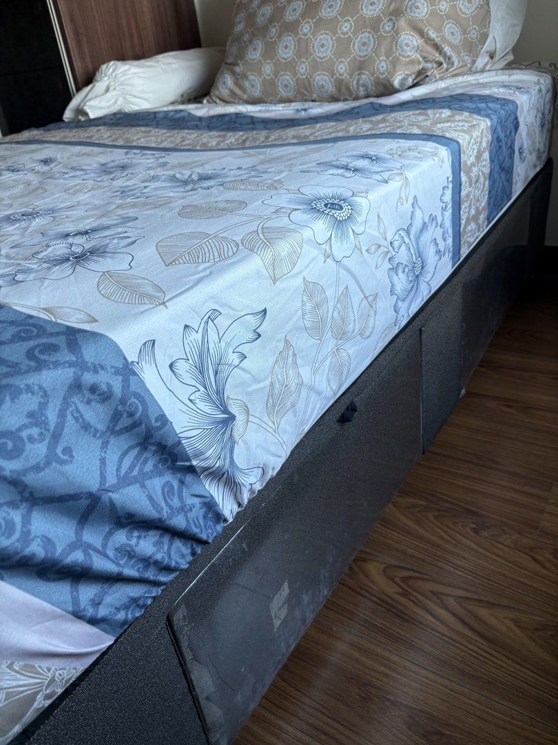 Double bed with mattress (Category: Bed Frames & Mattresses) located in Quezon City. Submitted by cattan7123 (Listing ID 1469542452, Image 3). Description: - Size: Queen size bed setup - Includes: Dark grey fabric base, comfortable mattress, and sturdy frame - Storage: Built-in pull-out drawers underneath for extra space - Bedding: Patterned bedsheets with blue and beige floral designs, pillows, and bolster included - Condition: Well-maintained, 