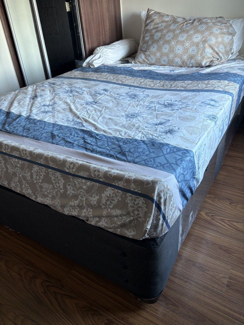 Double bed with mattress (Category: Bed Frames & Mattresses) located in Quezon City. Submitted by cattan7123 (Listing ID 1469542452, Image 1). Description: - Size: Queen size bed setup - Includes: Dark grey fabric base, comfortable mattress, and sturdy frame - Storage: Built-in pull-out drawers underneath for extra space - Bedding: Patterned bedsheets with blue and beige floral designs, pillows, and bolster included - Condition: Well-maintained, 