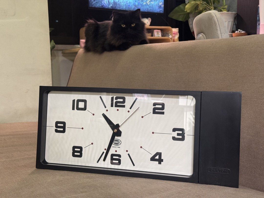 Dulton Double Sided Wall Clock (Category: Clocks) located in Malabon City. Submitted by dsrobles (Listing ID 1469533263, Image 3). Description: - Brand: Dulton (Established 1988) - Design: Modern industrial rectangular wall clock in sleek black - Dial: Clean white face with bold black numbering (1-12) - Versatile: Mounts easily on walls or stands upright on flat surfaces - Movement: Reliable battery-operated analog mechanism - Condition: Minimal 