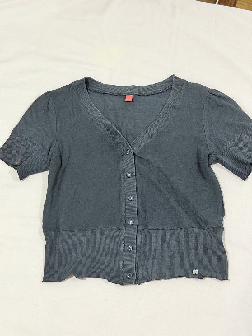 Espirit Grey Short Sleeve Button Cardigan V-Neck (Category: Blouses) located in Paranaque City. Submitted by hannahking36 (Listing ID 1469552632, Image 2). Description: - Brand: Esprit - Color: Dark grey - Material: Soft cotton blend - Style: Short sleeves, V-neckline, front button closure - Details: Wide ribbed hem and cuffs, small metal brand logo tag near the bottom - Flaw: Noticeable small reddish stain on the left sleeve cuff.