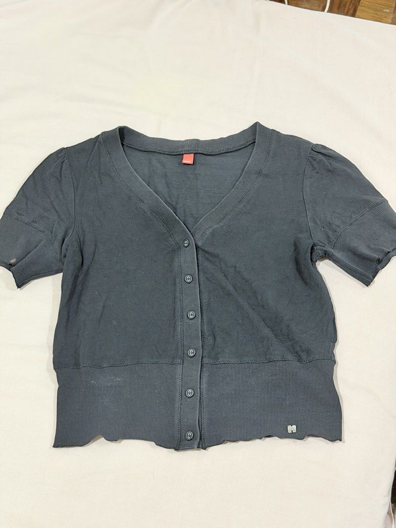 Espirit Grey Short Sleeve Button Cardigan V-Neck (Category: Blouses) located in Paranaque City. Submitted by hannahking36 (Listing ID 1469552632, Image 1). Description: - Brand: Esprit - Color: Dark grey - Material: Soft cotton blend - Style: Short sleeves, V-neckline, front button closure - Details: Wide ribbed hem and cuffs, small metal brand logo tag near the bottom - Flaw: Noticeable small reddish stain on the left sleeve cuff.