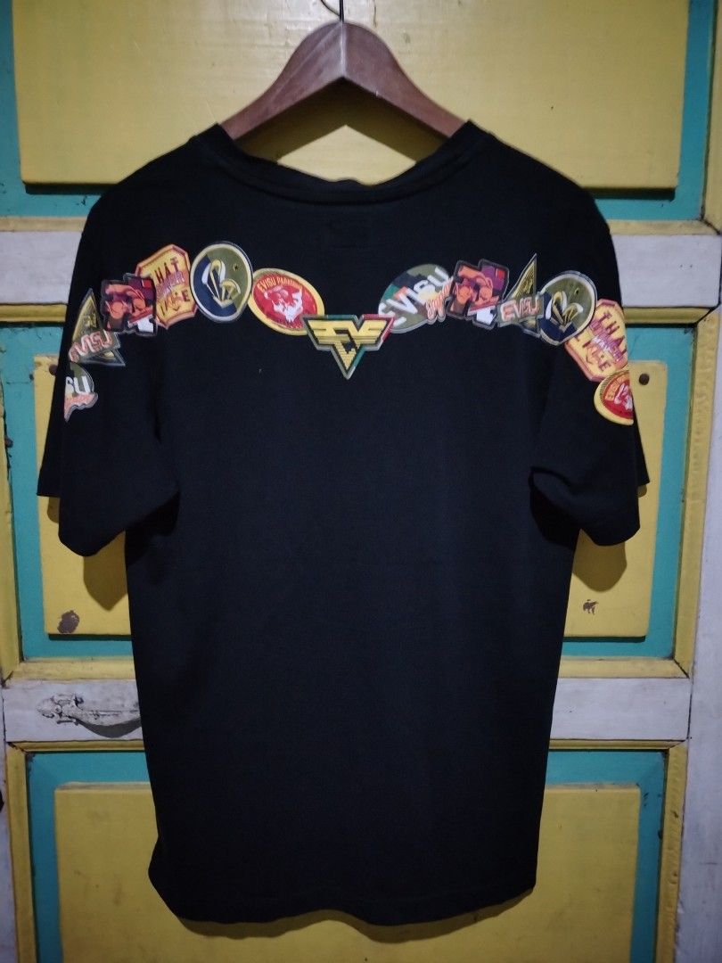 Evisu Force Parasquad Black Graphic T-Shirt (Category: Tshirts & Polo Shirts ) located in Caloocan City. Submitted by vincefresn21903 (Listing ID 1469500157, Image 2). Description: - Brand: Evisu - Model: Force Parasquad Tee - Color: Black - Size: Large (L) - Material: Comfortable cotton - Details: Bold white chest graphic, orange tag near hem, colorful embroidered patches across back shoulders, contrast stitching on inner collar - Condition: Exc