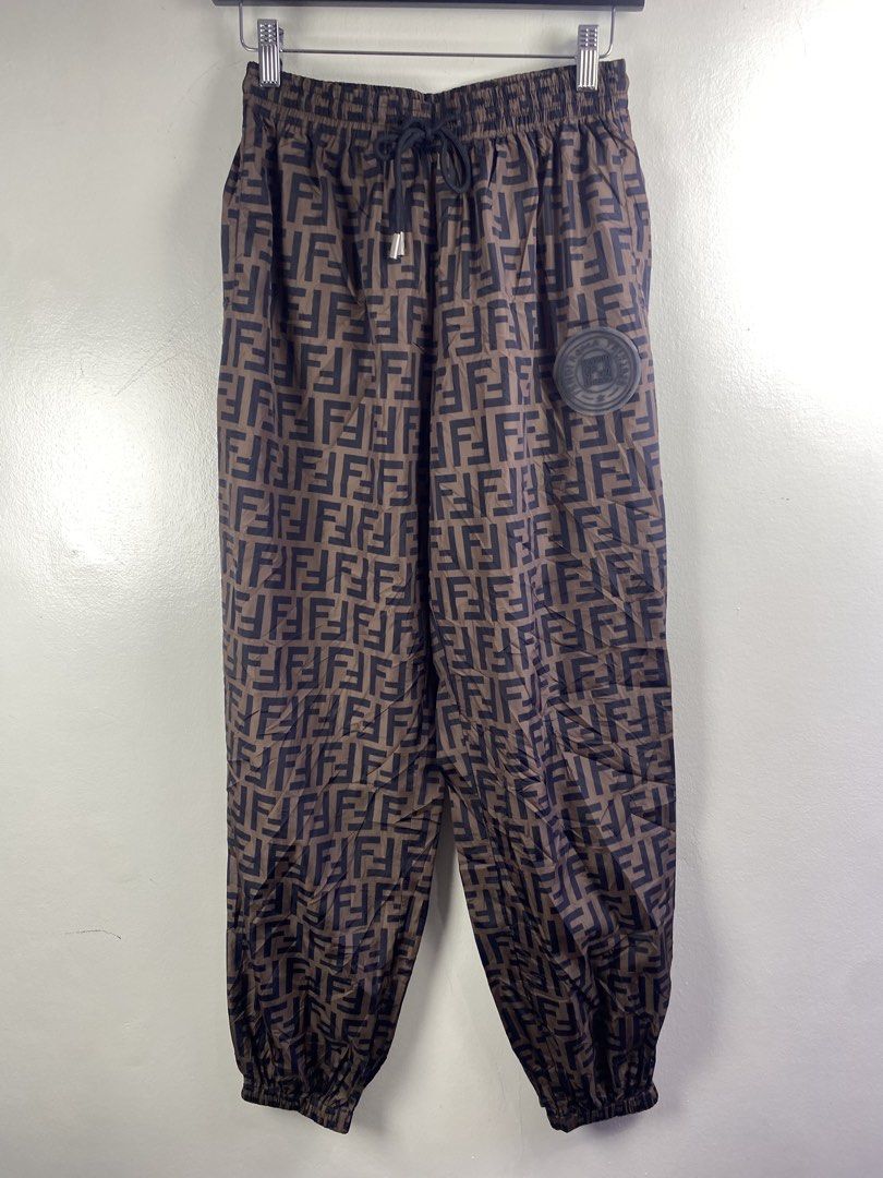 Fendi Roma FF Logo Brown Nylon Jogger Pants (Category: Joggers) located in Manila. Submitted by declutterpromax (Listing ID 1469450809, Image 1). Description: - Fendi Roma pants in brown with all-over FF logo pattern - Material: Lightweight and durable 100% nylon - Waistband: Elastic with adjustable black drawstring and metallic aglets - Details: Rubber Fendi Roma patch on the left leg, rear patch pocket, and ribbed ankle cuffs - Size: Large - Mo