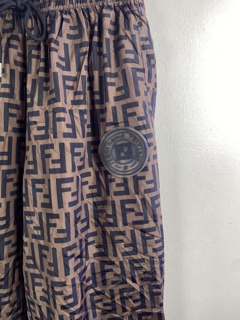 Fendi Roma FF Logo Brown Nylon Jogger Pants (Category: Joggers) located in Manila. Submitted by declutterpromax (Listing ID 1469450809, Image 2). Description: - Fendi Roma pants in brown with all-over FF logo pattern - Material: Lightweight and durable 100% nylon - Waistband: Elastic with adjustable black drawstring and metallic aglets - Details: Rubber Fendi Roma patch on the left leg, rear patch pocket, and ribbed ankle cuffs - Size: Large - Mo