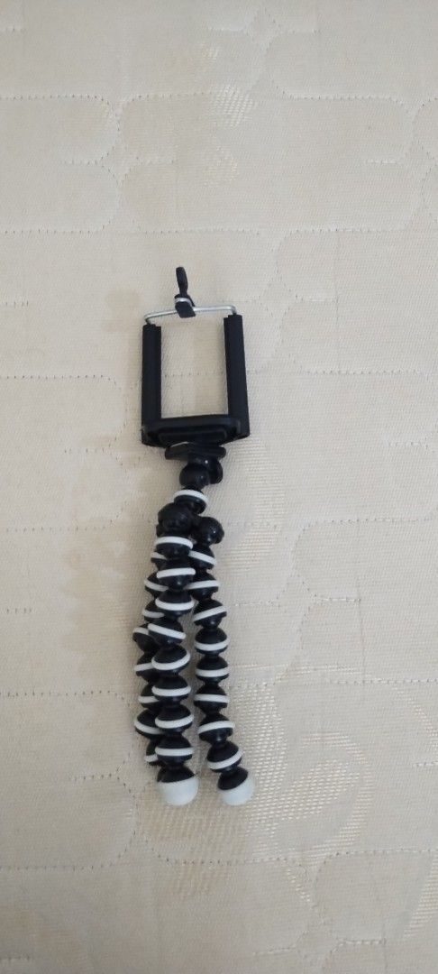 Flexible Gorilla Tripod with Phone Mount (Category: Tripods & Monopods) located in Makati City. Submitted by chamarket.2022 (Listing ID 1469420088, Image 1). Description: - Flexible octopus-style mini tripod in black and white - Includes adjustable phone holder clamp - Bendable legs wrap around poles, branches, or stand flat - Compact and lightweight for easy travel - Ideal for vlogging and mobile photography.