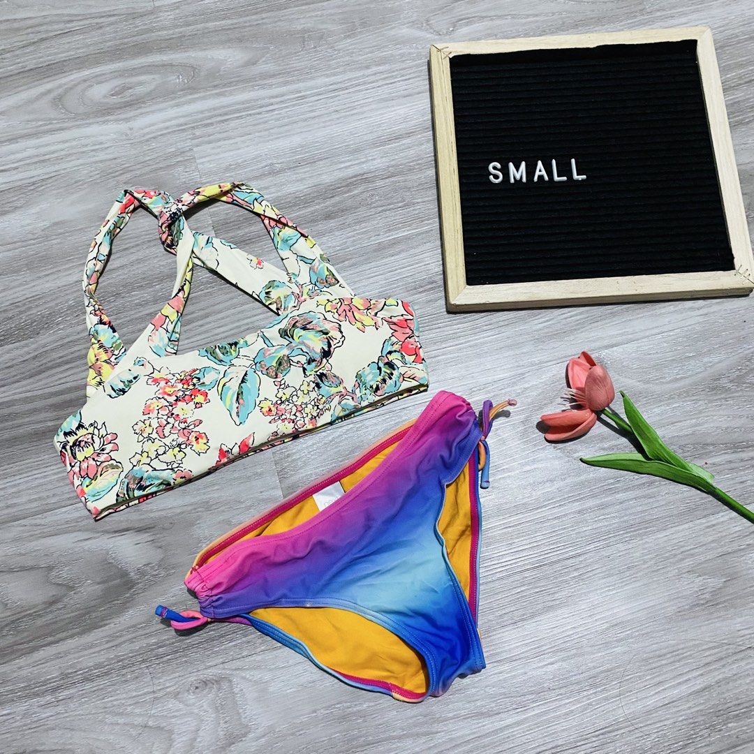 Floral Crop Top Bikini Set (Category: Bikinis & Swimsuits) located in Caloocan City. Submitted by lovemyclothes21 (Listing ID 1469496327, Image 1). Description: - Size: Small - Style: Two-piece swimsuit set - Top: Cream base with vibrant floral print and crisscross back straps - Bottoms: Pink, purple, and blue ombre gradient with side tie strings and solid yellow lining - Condition: Clean and beach-ready.