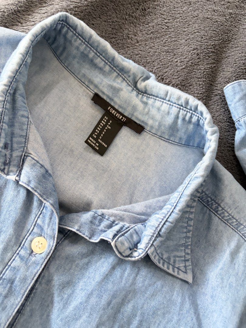 Forever 21 Light Blue Denim Button-Up Shirt (Category: Blouses) located in Quezon City. Submitted by marifavo (Listing ID 1469447387, Image 2). Description: - Brand: Forever 21 - Size: S - Color: Light blue denim - Fit: Relaxed fit with dropped shoulders - Details: Long sleeves with button cuffs, single chest pocket, rounded high-low hem - Material: Lightweight wash, perfect for versatile layering.