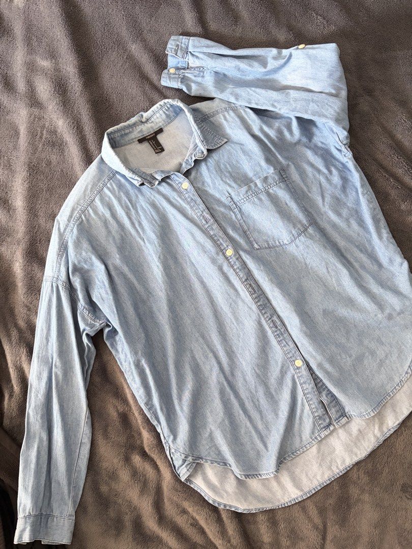 Forever 21 Light Blue Denim Button-Up Shirt (Category: Blouses) located in Quezon City. Submitted by marifavo (Listing ID 1469447387, Image 1). Description: - Brand: Forever 21 - Size: S - Color: Light blue denim - Fit: Relaxed fit with dropped shoulders - Details: Long sleeves with button cuffs, single chest pocket, rounded high-low hem - Material: Lightweight wash, perfect for versatile layering.