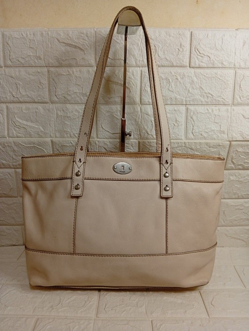Fossil Cream Leather Tote Bag (Category: Tote Bags) located in Las Pinas. Submitted by etoksi1234 (Listing ID 1469560131, Image 1). Description: Pre-owned Fossil cream or off-white pebbled cowhide leather shoulder tote bag featuring dual shoulder straps, silver-tone hardware, and a center oval Fossil logo plate. Issue on rubber lining..