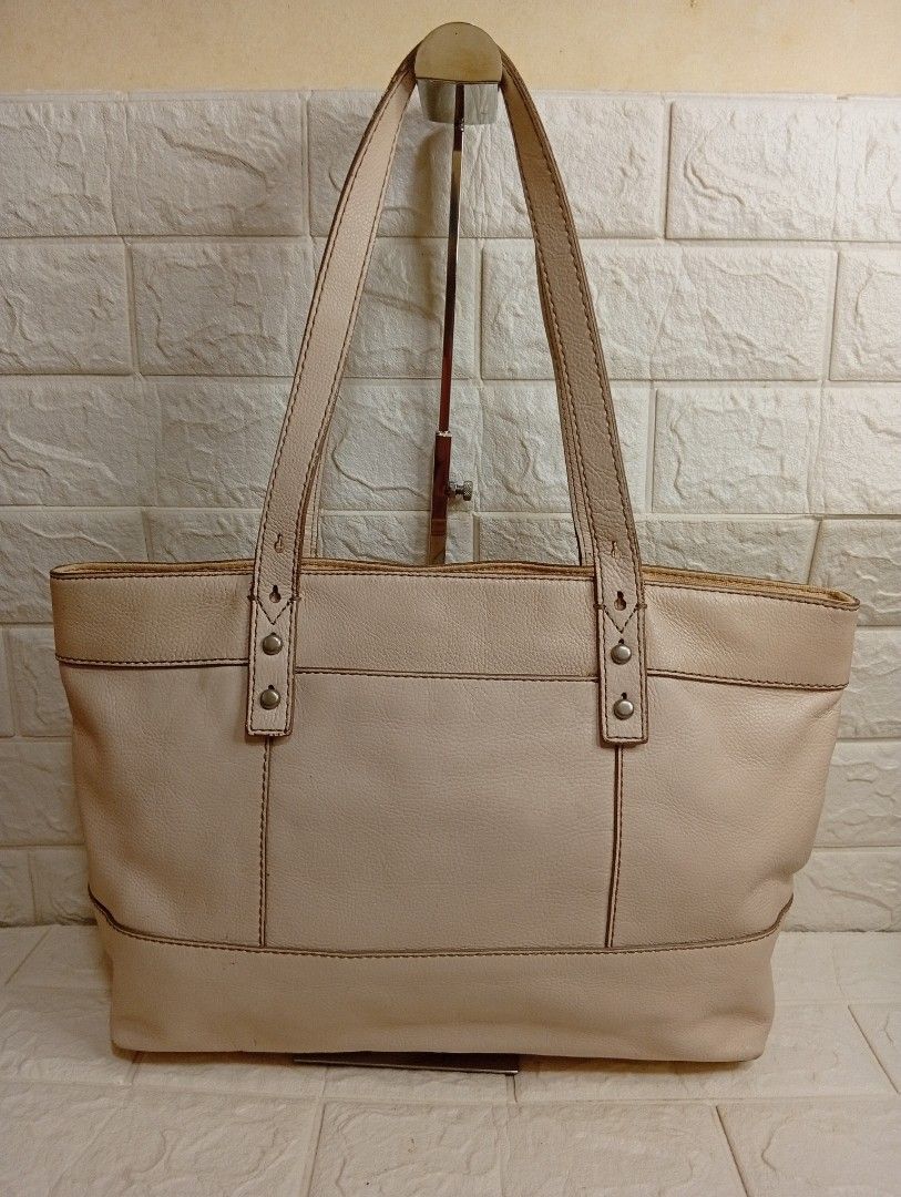 Fossil Cream Leather Tote Bag (Category: Tote Bags) located in Las Pinas. Submitted by etoksi1234 (Listing ID 1469560131, Image 2). Description: Pre-owned Fossil cream or off-white pebbled cowhide leather shoulder tote bag featuring dual shoulder straps, silver-tone hardware, and a center oval Fossil logo plate. Issue on rubber lining..