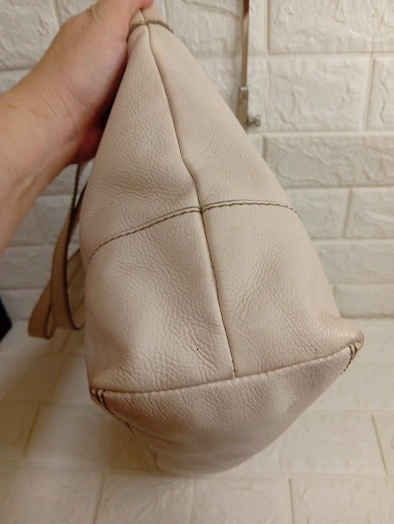 Fossil Cream Leather Tote Bag (Category: Tote Bags) located in Las Pinas. Submitted by etoksi1234 (Listing ID 1469560131, Image 3). Description: Pre-owned Fossil cream or off-white pebbled cowhide leather shoulder tote bag featuring dual shoulder straps, silver-tone hardware, and a center oval Fossil logo plate. Issue on rubber lining..
