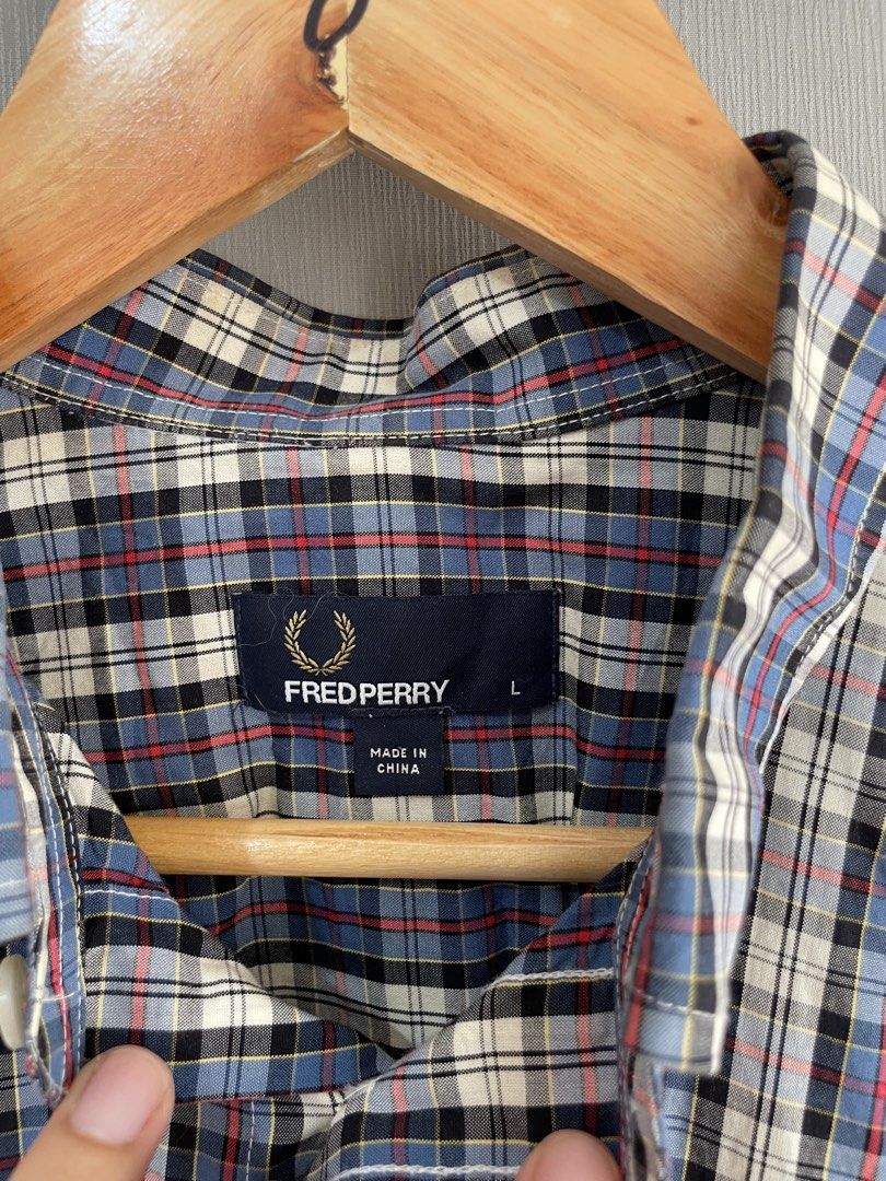 Fred Perry Plaid Short Sleeve Button Down Shirt Large (Category: Tshirts & Polo Shirts ) located in Mataasnakahoy. Submitted by zero4thrift (Listing ID 1469435634, Image 3). Description: - Brand: Fred Perry - Style: Short sleeve button-down shirt - Pattern: Multi-color plaid (Blue, White, Black, Red) - Size: L - Material: 100% Cotton (Made in China) - Features: Button-down collar, front button closure, and chest pocket with iconic embroidered lau