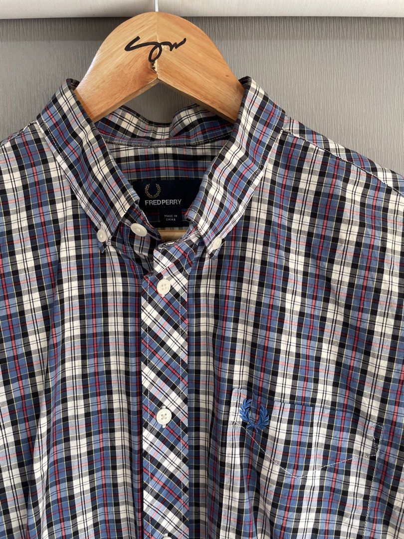 Fred Perry Plaid Short Sleeve Button Down Shirt Large (Category: Tshirts & Polo Shirts ) located in Mataasnakahoy. Submitted by zero4thrift (Listing ID 1469435634, Image 2). Description: - Brand: Fred Perry - Style: Short sleeve button-down shirt - Pattern: Multi-color plaid (Blue, White, Black, Red) - Size: L - Material: 100% Cotton (Made in China) - Features: Button-down collar, front button closure, and chest pocket with iconic embroidered lau