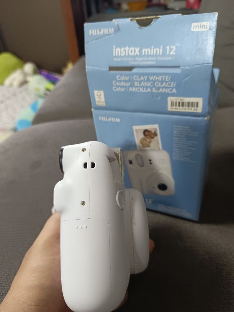 Fujifilm Instax Mini 12 Instant Camera Clay White (Category: Cameras) located in Agdangan. Submitted by gentleeagle_785f8e (Listing ID 1469397134, Image 3). Description: - Model: Fujifilm Instax Mini 12 - Color: Clay White - Condition: Camera body is clean and white; original box shows slight storage wear - Features: Easy point-and-shoot, twist lens to power on and activate close-up mode - Inclusions: Original box and wrist strap - Perfect for qu