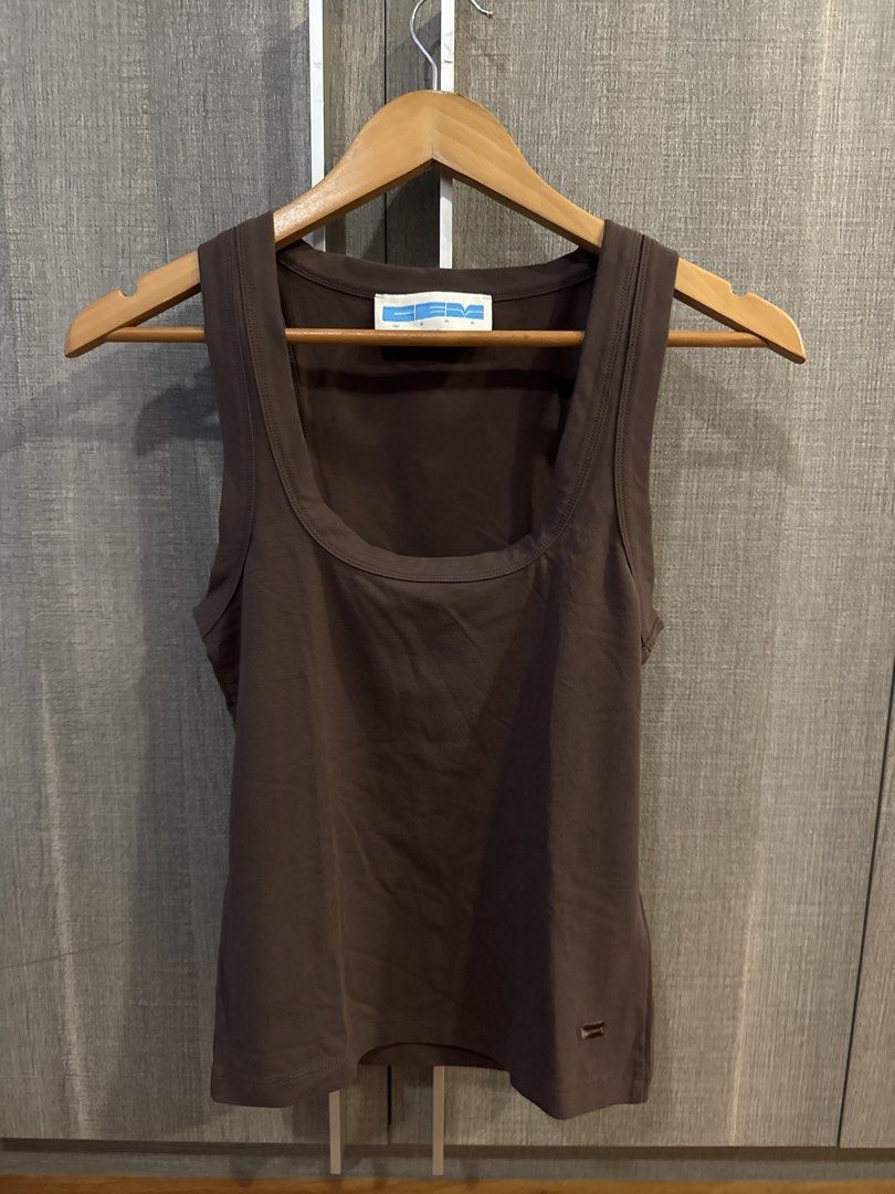 GEM Wear Tank Top (Category: Sleeveless) located in Makati City. Submitted by kkk.shops (Listing ID 1469510781, Image 1). Description: - Color: Brown - Design: Scoop neck with thick straps and ribbed trim - Details: Small branded patch near the bottom hem - Material: Soft fabric with a bit of stretch - Fit: Comfortable - Styling: Versatile piece for everyday layering or solo wear.