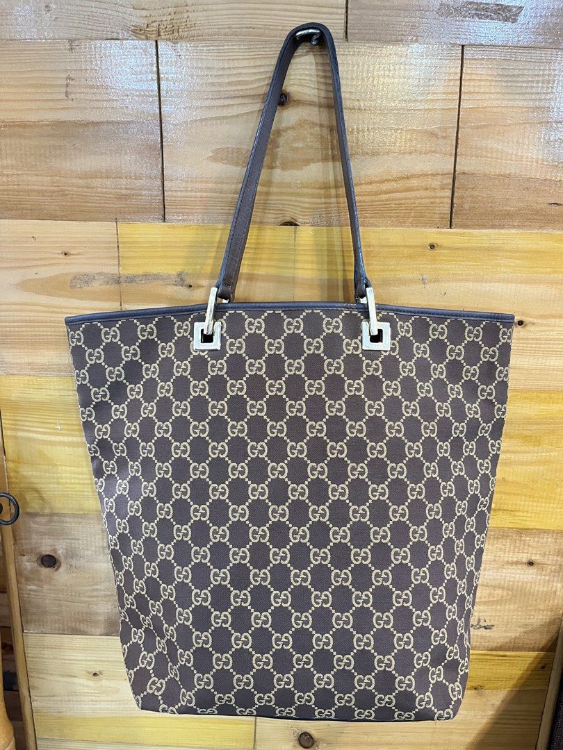 Gucci GG Canvas Tote Bag (Category: Tote Bags) located in Baguio. Submitted by elcie.08 (Listing ID 1469475567, Image 2). Description: - Authentic Gucci GG monogram canvas tote in classic brown - Dark brown leather trim and comfortable dual top handles - Elegant square hardware accents stamped with the brand name - Clean fabric interior lining with a zipped pocket - Includes classic leather heat stamp tag with serial numbers - Spacious and stylis
