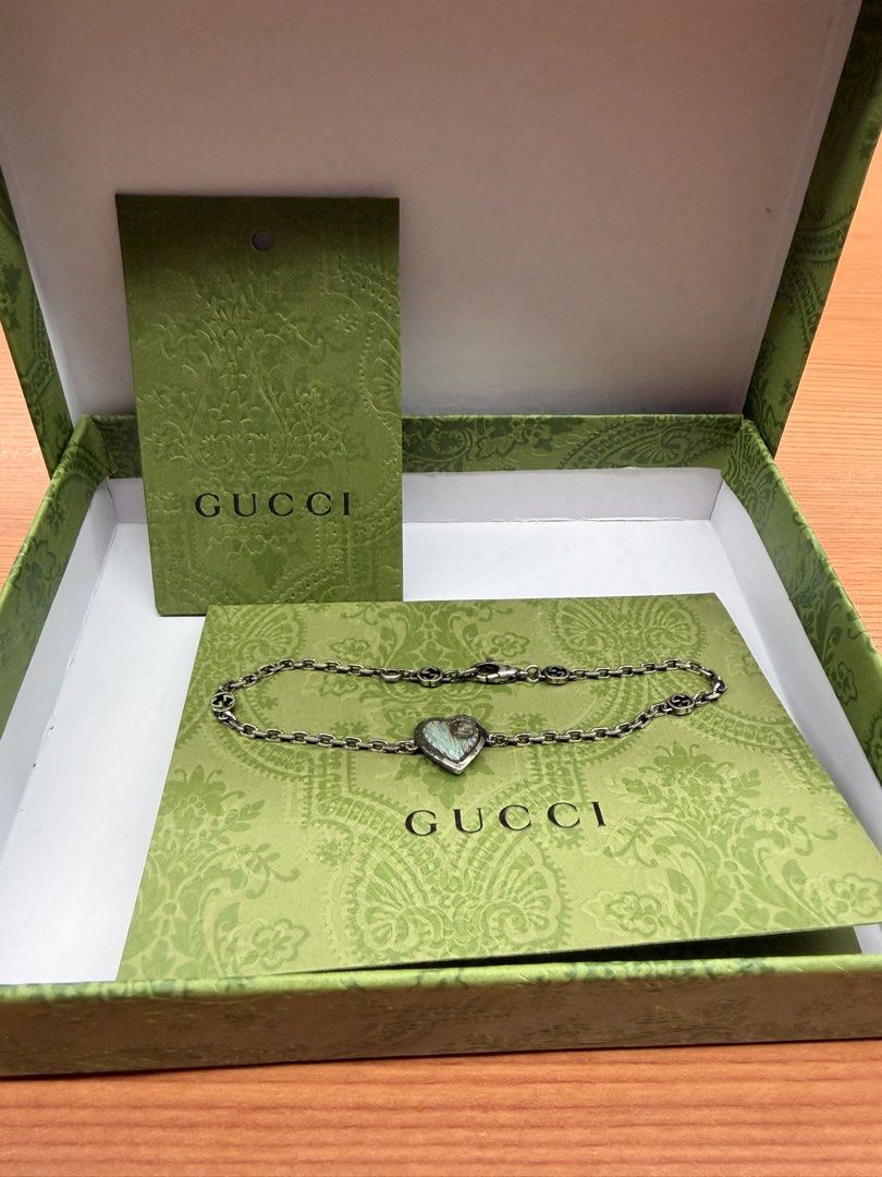 Gucci heart charm link bracelet with box (Category: Bracelets) located in Quezon City. Submitted by ellamenopi (Listing ID 1469398285, Image 1). Description: - Brand: Gucci - Material: Silver-tone metal - Design: Heart-shaped pendant with engraved GG detail and Interlocking G logos along the chain - Closure: Secure lobster clasp - Inclusion: Original green patterned Gucci box and matching cards - Condition: Excellent/Pristine - Mode of Payment: B