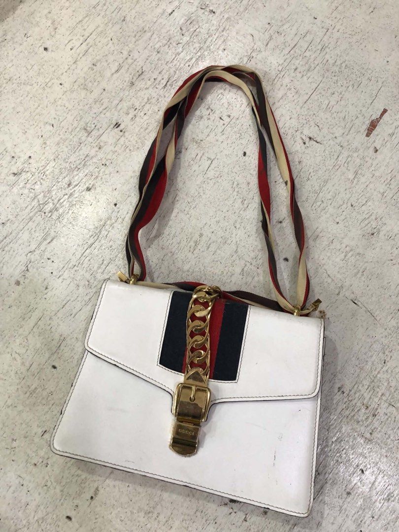 Gucci Sylvie White Leather Shoulder Bag (Category: Luxury Bags & Wallets) located in Bacolod City. Submitted by novymaesel14868 (Listing ID 1469397424, Image 2). Description: - Brand: Gucci - Model: Sylvie Shoulder Bag - Color: White leather with signature red and blue web stripe - Hardware: Gold-tone chain hardware and buckle closure - Interior: Fabric-lined with convenient zip pocket - Strap: Includes the classic striped shoulder strap - Condit
