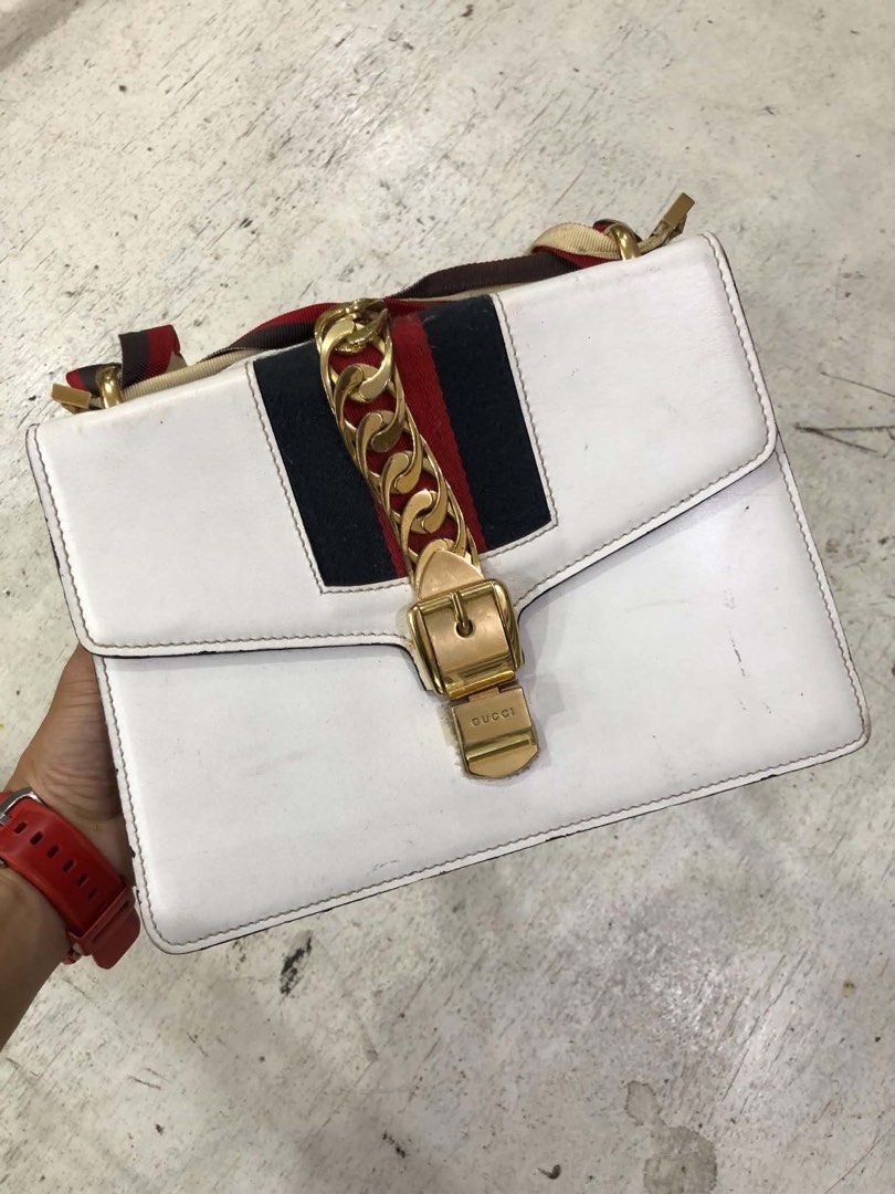 Gucci Sylvie White Leather Shoulder Bag (Category: Luxury Bags & Wallets) located in Bacolod City. Submitted by novymaesel14868 (Listing ID 1469397424, Image 1). Description: - Brand: Gucci - Model: Sylvie Shoulder Bag - Color: White leather with signature red and blue web stripe - Hardware: Gold-tone chain hardware and buckle closure - Interior: Fabric-lined with convenient zip pocket - Strap: Includes the classic striped shoulder strap - Condit
