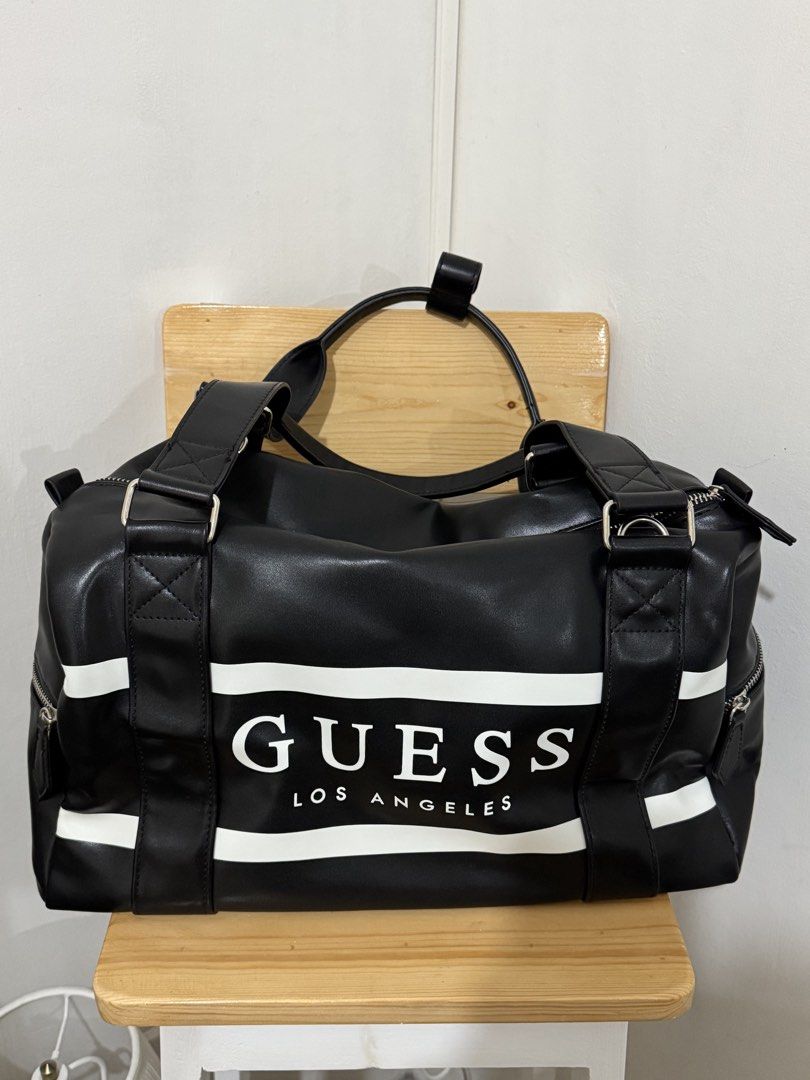 Guess Los Angeles Black Duffle Bag (Category: Shoulder Bags) located in Paranaque City. Submitted by shopdecalidad (Listing ID 1469438441, Image 1). Description: - Authentic Guess Los Angeles duffel bag in sleek black faux leather - Bold white horizontal stripes with signature branded lettering on the front - Secure top zipper closure with polished silver-tone hardware - Sturdy dual carry handles plus a matching adjustable logo shoulder strap - C