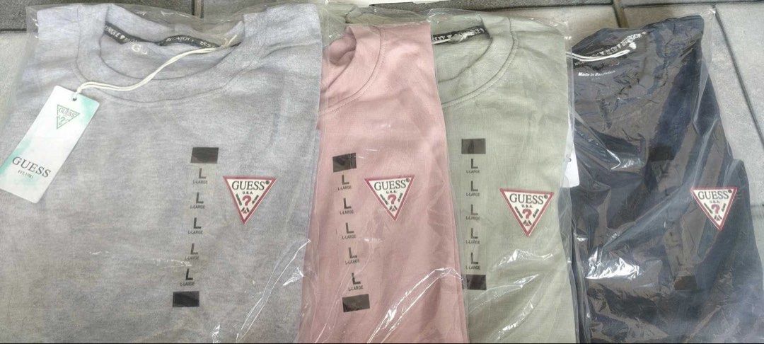 GUESS Women's Triangle Logo Tee Size L (Category: Shirts) located in Angeles City. Submitted by thon-thal (Listing ID 1469434808, Image 1). Description: - Brand: Guess - Style: Crewneck tee with embroidered red triangle logo - Fit & Material: Regular fit, 100% cotton - Size: Large - Colors Available: Heather grey, dusty pink, sage green, and dark navy - Condition: Brand new, still in original plastic packaging with swing tags attached -green and 