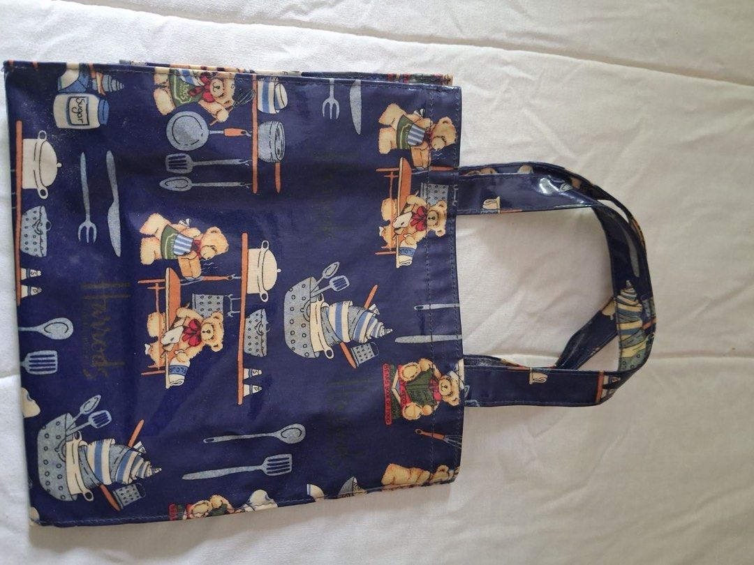 Harrods Teddy Bear Kitchen Print PVC Tote Bag (Category: Tote Bags) located in Muntinlupa City. Submitted by everythingmustgo_8475da (Listing ID 1469484568, Image 1). Description: - Authentic Harrods tote bag in a stylish dark blue color - Glossy PVC material featuring an adorable teddy bear and kitchenware print - Sturdy double handle straps for comfortable carrying - Spacious size ideal for daily errands, groceries, or books - Wipe-clean surfac