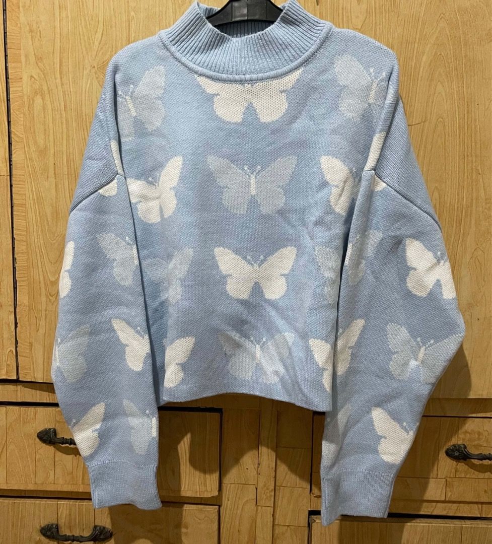 H&M Light Blue Butterfly Knit Sweater (Category: Longsleeves) located in Antipolo. Submitted by annedeclutterss (Listing ID 1469463333, Image 1). Description: - Color: Light blue with all-over white butterfly pattern - Fit: Cropped fit with pullover style - Neckline: Mock neck collar - Sleeves: Long sleeves - Material: Super soft and comfortable - Perfect for: Casual chilly days and pairing with jeans.