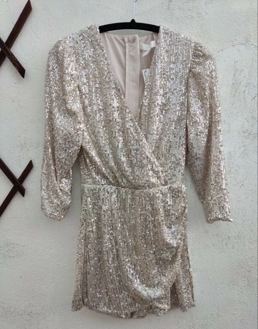 H&M Gold/Silver Sequin Wrap Playsuit (Category: Rompers) located in Quezon City. Submitted by gilliesshoppe (Listing ID 1469566279, Image 3). Description: - Style: Silver sequin playsuit with long sleeves and crossover wrap front. Zipper enclosure at the back. It somewhat has a gold reflection because of the nude base of the sequin cloth. (Check last photo for color comparison) - Size 42 (best fits large to xl size) - Details: V-neckline, gathere