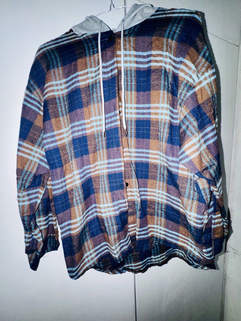 Hooded Plaid Flannel Shirt (Category: Coats, Jackets and Outerwear) located in Valenzuela. Submitted by styledtwicethriftshop (Listing ID 1469490134, Image 2). Description: Button-down flannel shirt with an attached grey hood and drawstring. Plaid pattern in blue, black, and white tones. Long sleeves with button cuffs. Regular fit, easy to layer over tees. Fabric feels soft and lightweight..