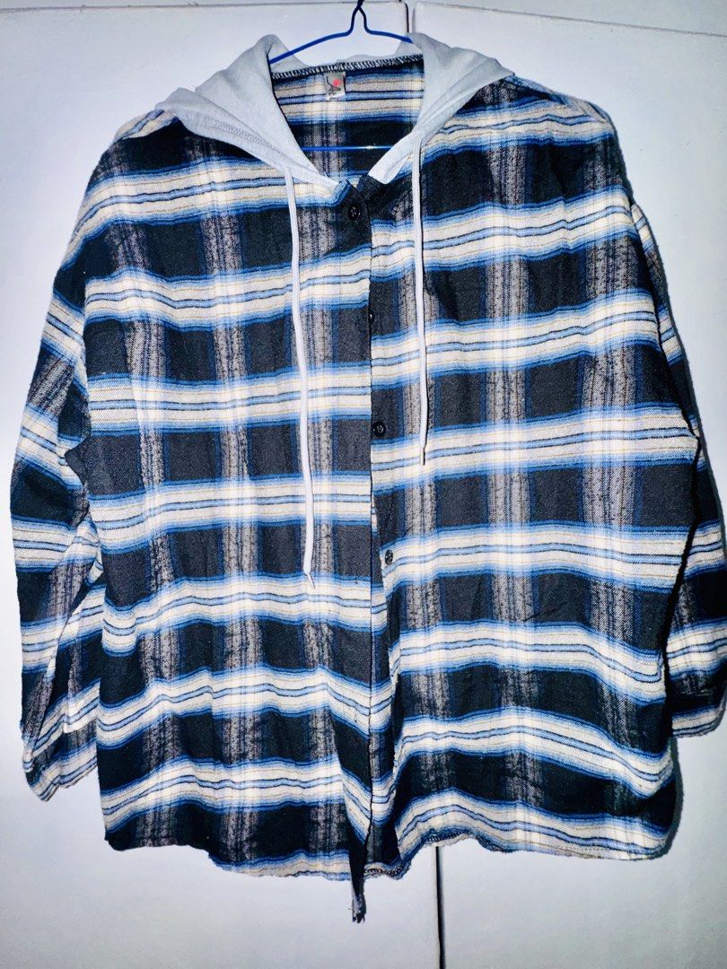 Hooded Plaid Flannel Shirt (Category: Coats, Jackets and Outerwear) located in Valenzuela. Submitted by styledtwicethriftshop (Listing ID 1469490134, Image 1). Description: Button-down flannel shirt with an attached grey hood and drawstring. Plaid pattern in blue, black, and white tones. Long sleeves with button cuffs. Regular fit, easy to layer over tees. Fabric feels soft and lightweight..