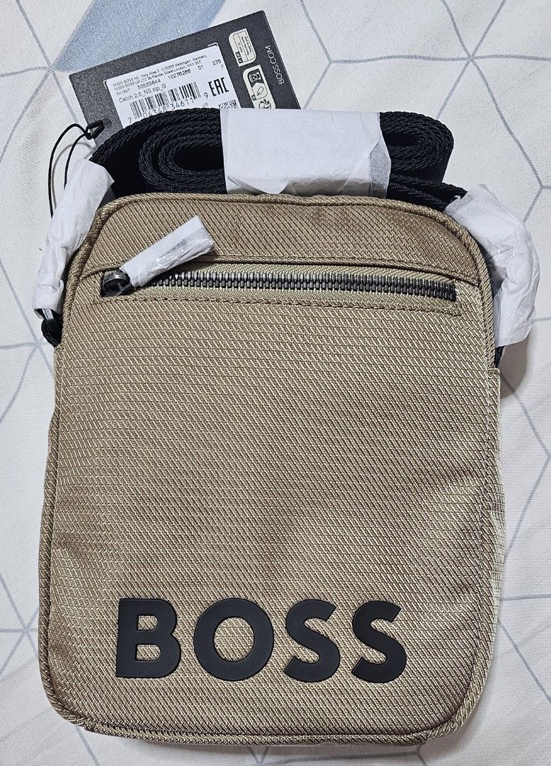 HUGO BOSS Crossbody Bag (Category: Sling Bags) located in Davao. Submitted by dahl957172787 (Listing ID 1469513564, Image 1). Description: - Brand new with original retail tags attached - Authentic HUGO BOSS Catch 2.0 NS zip crossbody bag - Sleek metallic khaki fabric texture with black rubberized BOSS logo - Convenient front zip pocket for easy access - Adjustable black strap (protective paper still wrapped around buckles and zipper puller).