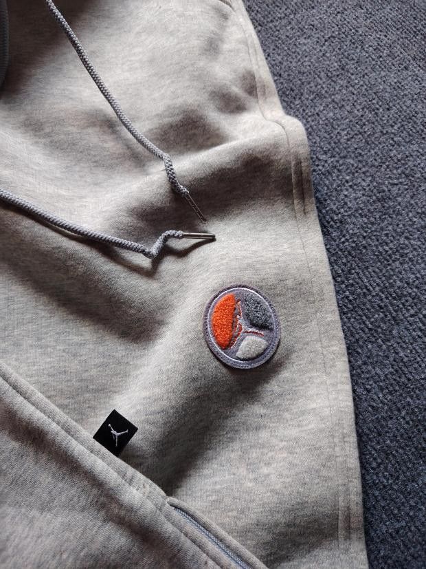 Jordan Grey Fleece Sweatpants Size M (Category: Joggers) located in Manila. Submitted by carldavebanay (Listing ID 1469554560, Image 3). Description: - Brand: Jordan - Color: Grey with orange trim accents - Size: Medium (tag attached) - Material: Soft interior fleece lining for maximum warmth - Features: Adjustable drawstring waistband, side pockets, and a secure buttoned back pocket - Details: Unique circular patch on the left leg - Cuffs: Ribbe