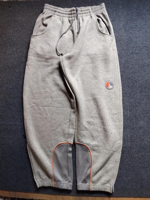 Jordan Grey Fleece Sweatpants Size M (Category: Joggers) located in Manila. Submitted by carldavebanay (Listing ID 1469554560, Image 1). Description: - Brand: Jordan - Color: Grey with orange trim accents - Size: Medium (tag attached) - Material: Soft interior fleece lining for maximum warmth - Features: Adjustable drawstring waistband, side pockets, and a secure buttoned back pocket - Details: Unique circular patch on the left leg - Cuffs: Ribbe
