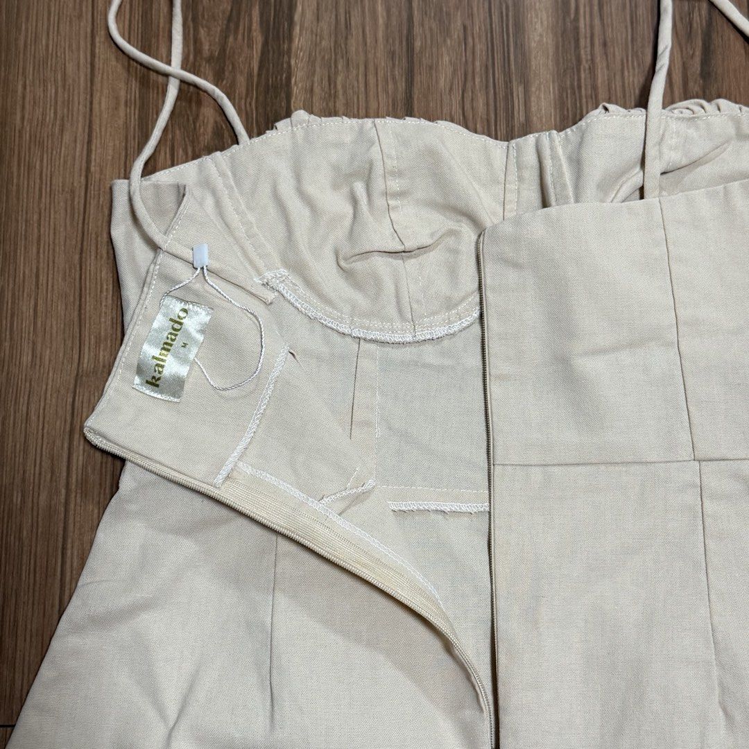 Kalmado Beige linen Spaghetti Strap Mini Dress Size M (Category: Dresses) located in Binangonan. Submitted by curatedbyjuys (Listing ID 1469441649, Image 3). Description: - Brand: Kalmado - Color: Neutral beige - Size: Medium (M) - Design: Spaghetti straps, gathered corset-style bust, and back zipper closure - Detail: Chic front side slit on the hem - Material: Lightweight fabric, perfect for casual outings or date nights.