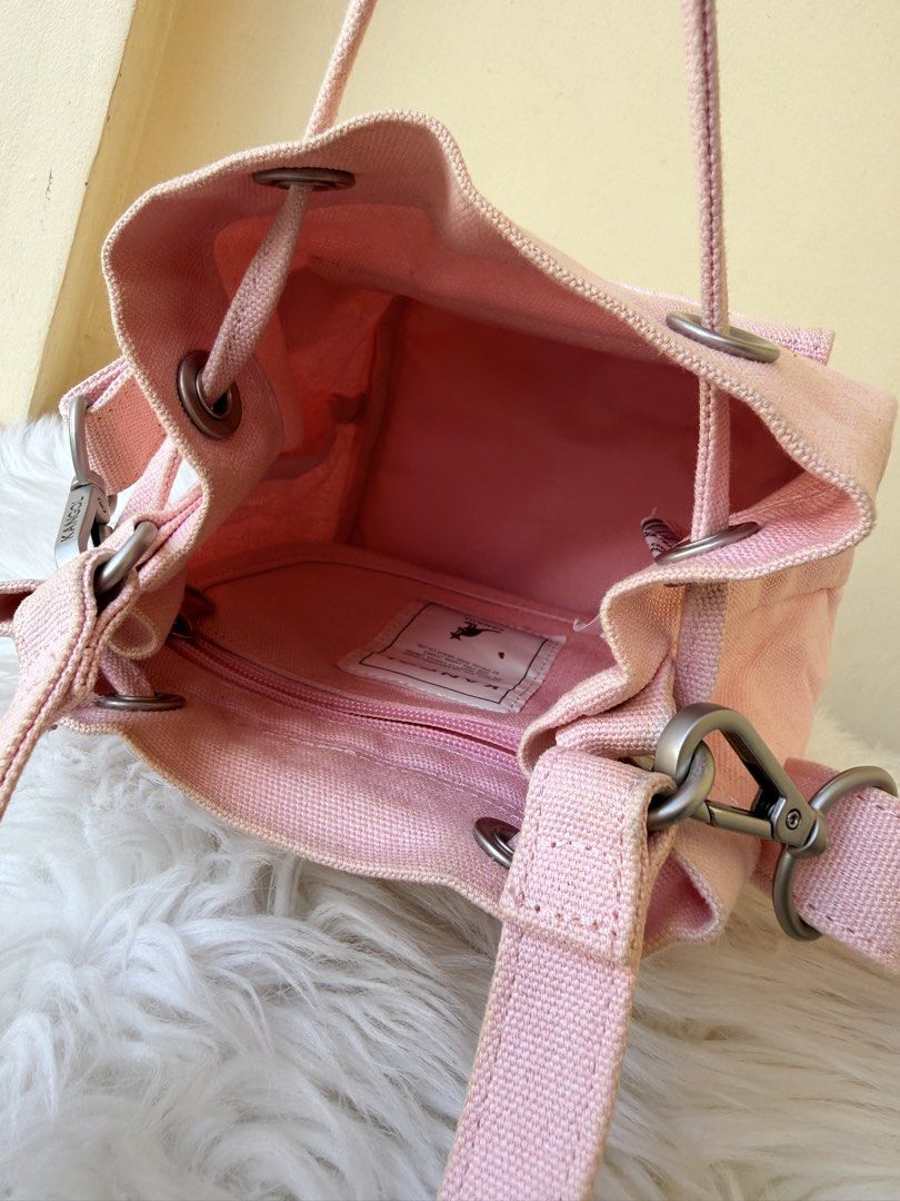 Kangol Pink Canvas Bucket Bag (Category: Shoulder Bags) located in Solano. Submitted by hayami. (Listing ID 1469436736, Image 2). Description: - Brand: Kangol - Color: Pink - Material: Durable canvas - Closure: Drawstring top - Pockets: Handy front pocket with logo patch, plus an internal zipper compartment for small items - Carrying Options: Dual top handles and a detachable shoulder strap - Condition: Light staining on the internal fabric patch
