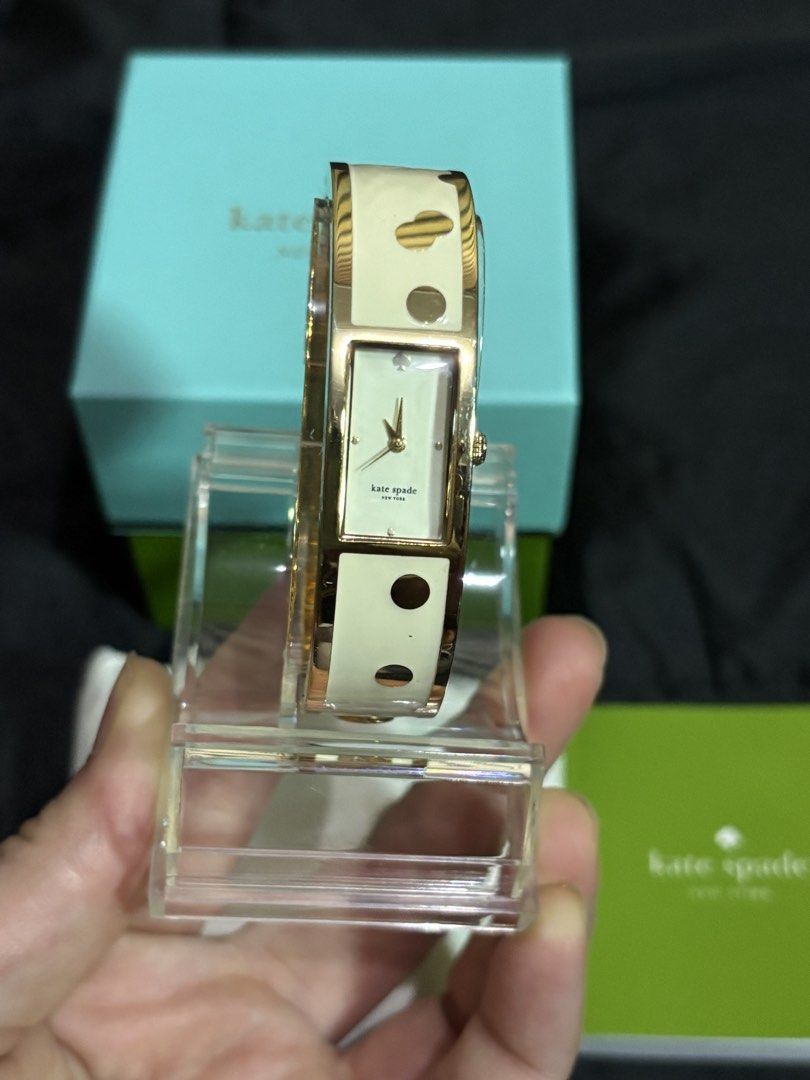Kate Spade New York Confetti Carousel Bangle Watch (Category: Women's Watches) located in Caloocan City. Submitted by berndale_closet (Listing ID 1469570041, Image 3). Description: - Brand: Kate Spade New York (Confetti Carousel Bangle Watch) - Dial: Rectangular cream-white analog with signature spade logo at 12 o'clock - Case: Gold-plated stainless steel (16mm width) - Strap: Rigid hinged gold-tone bangle inlaid with ivory enamel and gold polka 