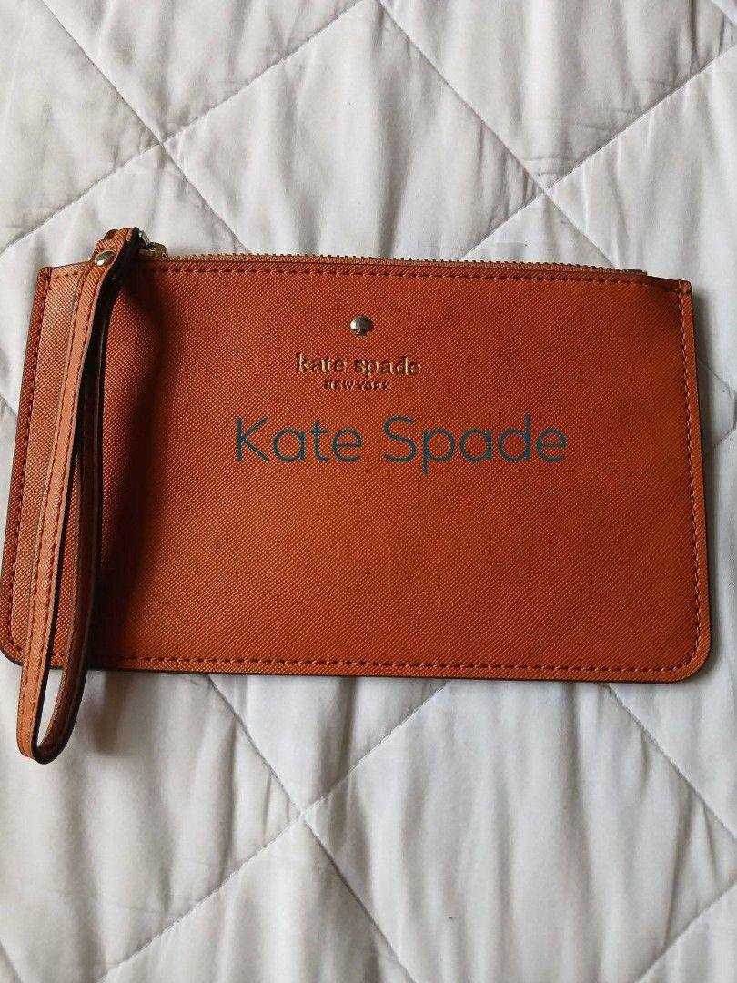 Kate Spade Orange Leather Wristlet Pouch (Category: Purses & Pouches) located in Manila. Submitted by purefire_c06a2b (Listing ID 1469402687, Image 1). Description: - Authentic Kate Spade New York wristlet in a vibrant orange shade - Durable Saffiano leather texture with clean edge stitching - Secure zip-top closure and convenient attached wrist strap - Elegant gold-tone hardware and iconic metal spade logo pin - Compact size designed to fit your