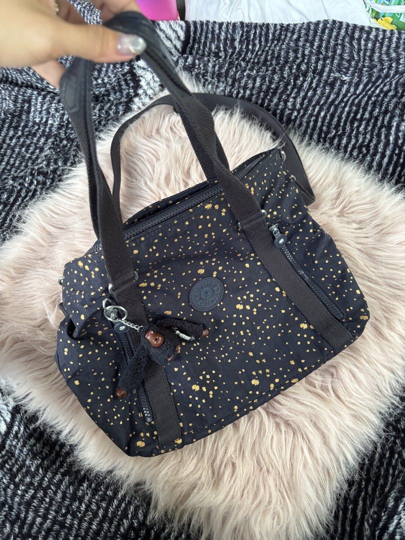Kipling Black Gold Splatter Tote Bag (Category: Tote Bags) located in Digos. Submitted by kathydiane76376 (Listing ID 1469427782, Image 2). Description: - Brand: Kipling - Color/Design: Classic black with stylish gold splatter pattern - Material: Durable, lightweight nylon - Straps: Dual top handles + adjustable, detachable shoulder strap - Pockets: Multiple exterior zip pockets for easy organization - Closure: Secure top zip main compartment - I