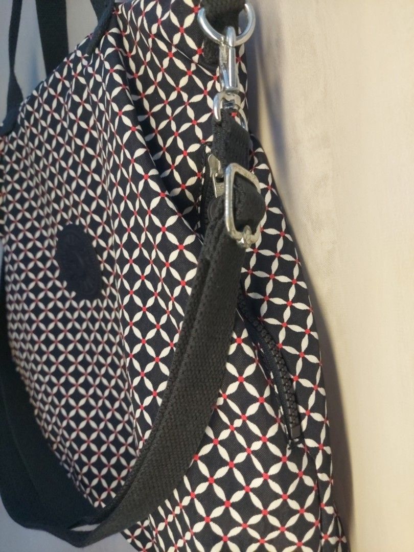 Kipling patterned tote bag with handles and strap (Category: Tote Bags) located in Quezon City. Submitted by never_a_clutter (Listing ID 1469512797, Image 3). Description: - Brand: Kipling - Design: Dark navy blue, white, and red geometric pattern with round front logo patch - Material: Durable fabric throughout - Carry Options: Sturdy dark blue fabric carry handles and an adjustable shoulder strap - Hardware: Silver-tone accents - Inclusion: Mat