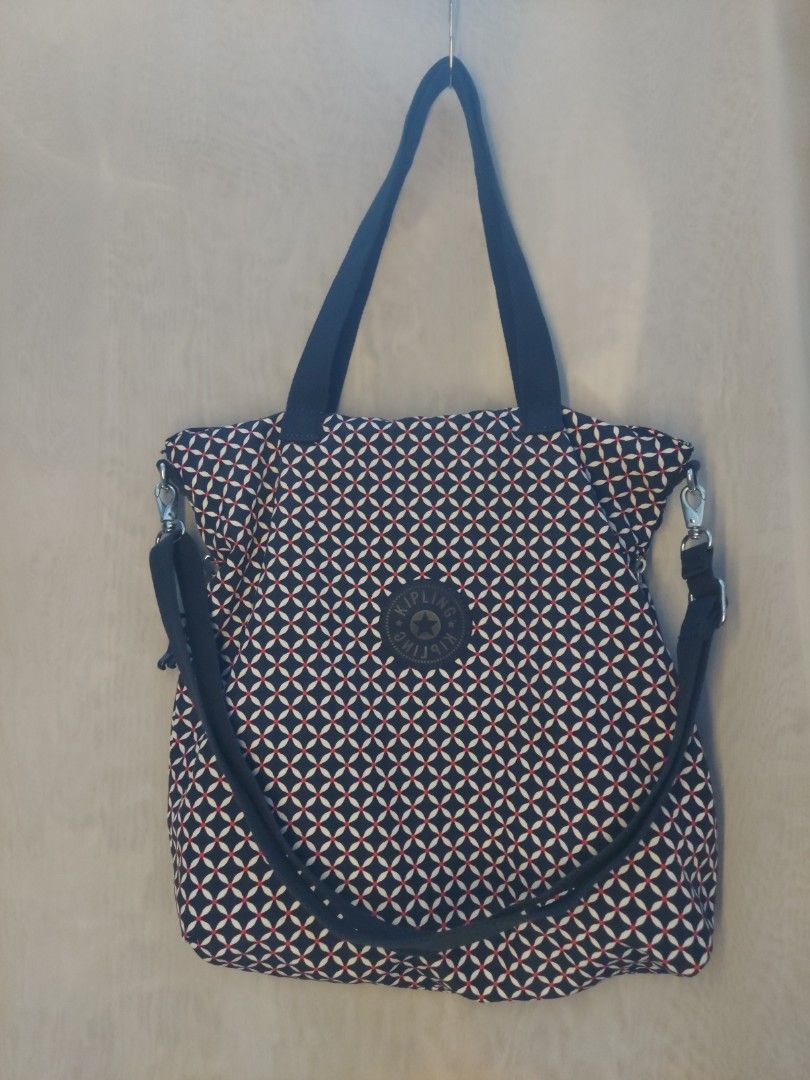 Kipling patterned tote bag with handles and strap (Category: Tote Bags) located in Quezon City. Submitted by never_a_clutter (Listing ID 1469512797, Image 1). Description: - Brand: Kipling - Design: Dark navy blue, white, and red geometric pattern with round front logo patch - Material: Durable fabric throughout - Carry Options: Sturdy dark blue fabric carry handles and an adjustable shoulder strap - Hardware: Silver-tone accents - Inclusion: Mat
