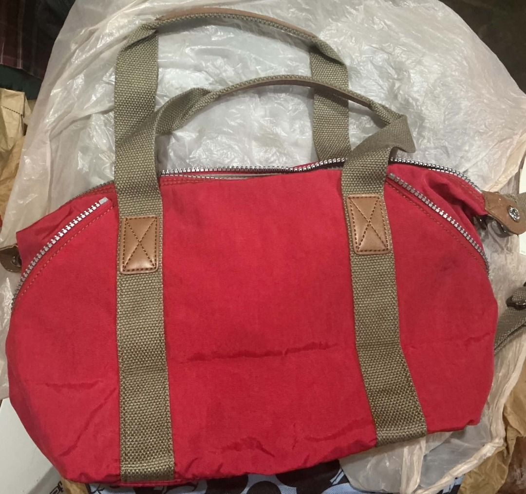 Kipling Red Shoulder Bag Tote (Category: Shoulder Bags) located in Muntinlupa City. Submitted by reicysangabol.778 (Listing ID 1469424390, Image 2). Description: - Brand: Kipling - Condition: Brand new with tags attached - Color: Bright red with contrasting green handles and strap - Includes: Signature fuzzy monkey keyring accessory - Storage: Multiple zippered compartments for easy organization - Details: Front leather logo patch -Item legit fro