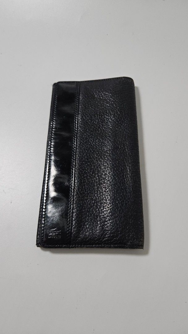 Lacoste black leather long wallet (Category: Wallets & Card Holders) located in Alfonso. Submitted by jbcamet (Listing ID 1469515875, Image 1). Description: - Authentic Lacoste men's long wallet - Genuine black pebbled leather with smooth patent leather accent - Features debossed crocodile logo and Lacoste lettering - Multiple card slots, bill compartments, and slip pockets - Classic bi-fold design for cards, cash, and documents.