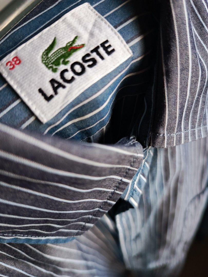 Lacoste Striped Long Sleeve Button Down Shirt Size 38 (Category: Tshirts & Polo Shirts ) located in Marikina City. Submitted by wisebuytoo (Listing ID 1469435149, Image 3). Description: - Brand: Lacoste - Style: Blue and white striped long sleeve shirt - Size: Tagged Size 38 - Details: Button-down front, classic collar, single chest pocket with iconic embroidered crocodile logo - Fabric: Lightweight with vertical stripes - Condition: Clean overal