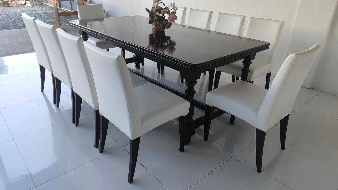 Large dark wood dining table with eight white chairs (Category: Tables & Sets) located in Manila. Submitted by roveeeeelen_06 (Listing ID 1469418864, Image 3). Description: - Elegant rectangular dining table with a dark polished wood finish - Includes 8 matching high-back chairs upholstered in smooth white synthetic leather - Sturdy frame that comfortably seats 8 people, ideal for family gatherings - Overall clean upholstery - Minor scuffs on tab